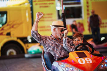 Grandfather and grandson having fun and spending good quality time together in amusement park. They...