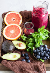 Purple smoothie with fresh blueberries, mint, avocado and grapefruit in wooden tray. Healthy food. Clear eating selection. Summer breakfast or lunch.