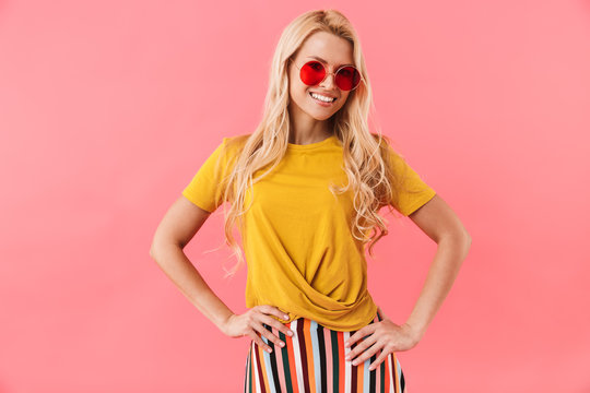 Smiling blonde woman in sunglasses with arms on hips