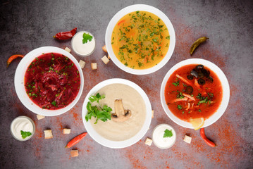 Set of soups from worldwide cuisines, healthy food. Cream soup with mushrooms,solyanka, russian borscht, chicken soup on silver background. Top view.