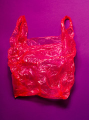 Red plastic bag on purple background. Bright background.