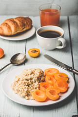 Porridge with apricot, coffee, glass of juice and croissant