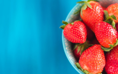 fresh bright strawberries in a bowl top view on a blue background