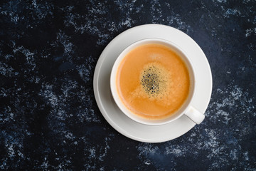 White cup of coffee on black. Top view, cup on wooden table, break or breakfast