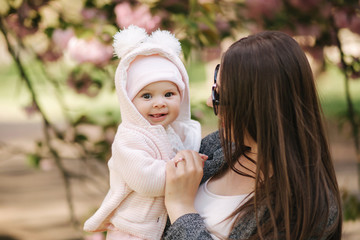 Portrait of mother and her little baby girl. Beautiful mom and cute baby. Mother hud her daughter. Baby dressed in peanch colour hat and smile