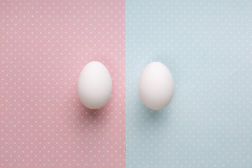 Two eggs on pastel pink and blue background. Top view. Gender and newborn concept. 