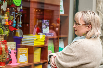 Portrait of a thick blonde woman in a trench coat of beige and a green dress. The girl reads the book. Trends 2019. Fashion photography on the street