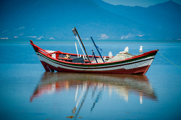 Barco de pesca com reflexo e céu azul