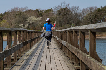 Woman jogging over a wooden bridge