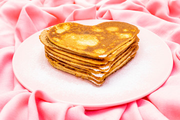 Heart shaped pancakes for romantic breakfast on rosy plate. Shrovetide (carnival) concept. On pink cloth linen background