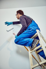 Worker painting walls inside the house - renovation fixes.