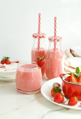 Strawberry smoothie or milkshake in a glass on marble background. Healthy food for breakfast and snack. copy space