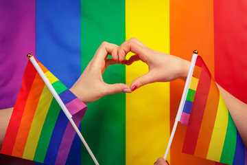 Hand making a heart sign with gay pride LGBT rainbow flag
