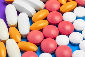set of multi-colored tablets and capsules on a blue background