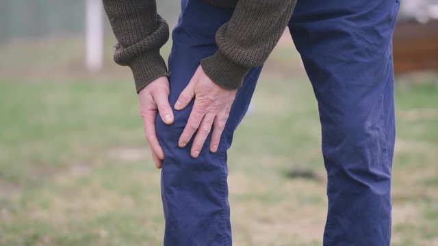 Closeup of a man having knee pain from an injury massaging himself.