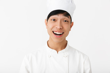 Image of asian happy chief man in white cook uniform smiling at camera
