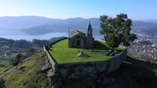 Aerial orbital of old hilltop Peneda chapel and Redondela town, Spain