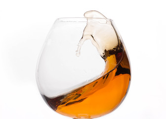 splash of cognac in transparent glass isolated on white