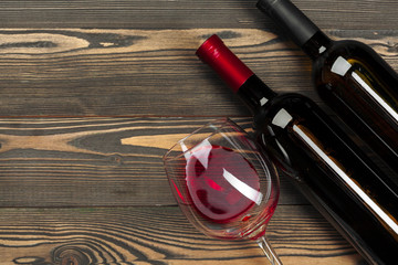 glass and bottle with red wine on wooden background, top view