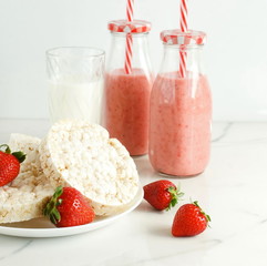 healthy rice waffles like breakfast, snacks and fresh strawberries, strawberry smoothies and a glass of milk on marble table, background. copy space
