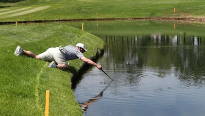 Deurstickers A golfer reaches into a pond to retrieve his ball © Ron Alvey
