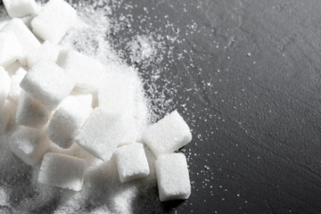 Sugar lumps piled up together against a black background