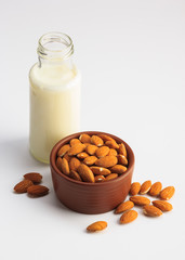 Milk and bowl of almonds isolated on a white background
