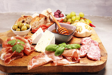Cutting board with prosciutto, salami, cheese,bread and olives on dark stone background