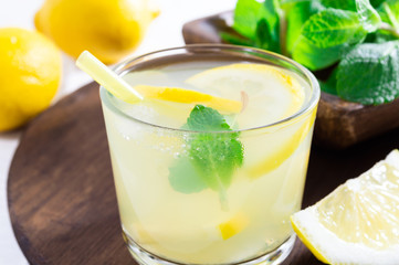 Summer drink of lemon and mint, or lemonade, on dark wooden table.