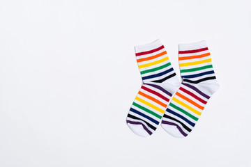 Two fabric white socks with colorful striped pattern over white background with copy space. Textile warm clothes for feet