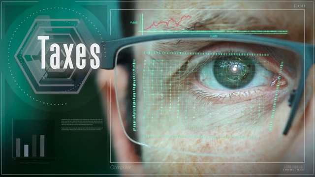A close up of a businessman eye controlling a futuristic computer system with a Taxes Business concept.