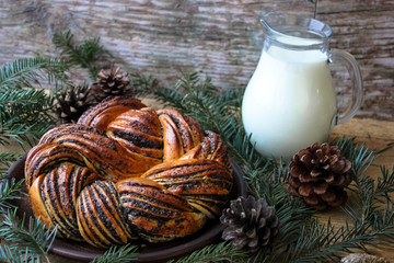 Traditional lithuanian poppy seed cake on a clay plate stands behind the fir branch. Selective focus