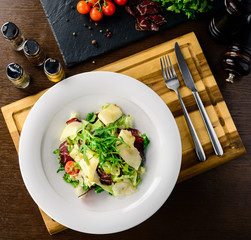 Salad with baked beet, blue cheese, ham and green mix with pesto
