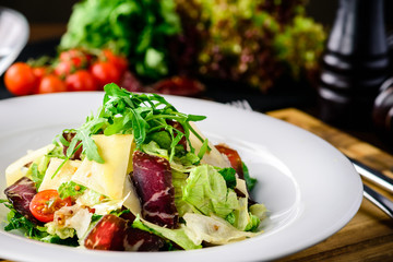 Salad with baked beet, blue cheese, ham and green mix with pesto