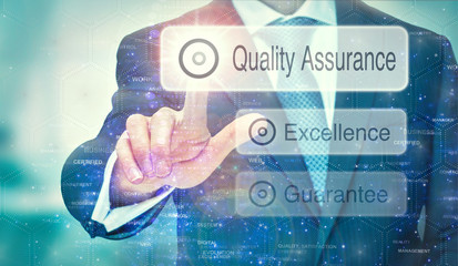 A business man selection a Quality Assurance button on a futuristic display with a concept written on it.