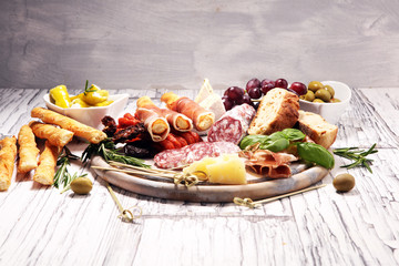 Fototapeta na wymiar antipasto various appetizer. Cutting board with prosciutto, salami, cheese, bread and olives on white wooden background