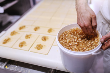 Caucasian hardworking baker making rolls with jam. Bakehouse interior.