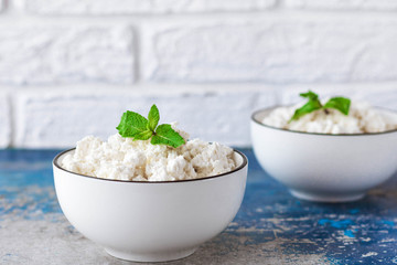 Cottage cheese with mint leaves on a light background in white bowl