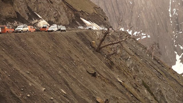 Medium low-angle still shot of vehicles passing each other along the dangerous Zoji La, Ladakh. Glacier flow to the road from an ar te forces vehicles from one side to give way, Ladakh 