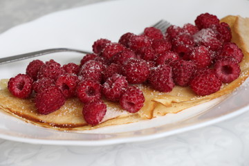 Delicious pancake with fresh raspberries on plate