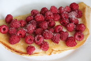 Delicious pancake with fresh raspberries on plate