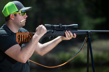 A man working the bolt on a rifle with the ejected shell in the air.