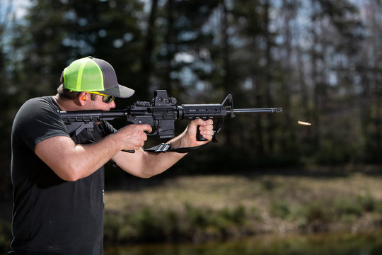 A man shooting an AR carbine with the empty cartridge case in the air.