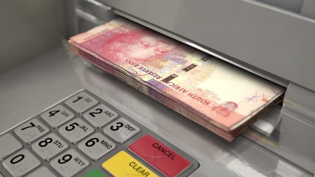 A closeup view of an atm facade with an illuminated sceen and keypad and a wad of south african rand banknotes being ejected from the cash slot 