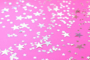Obraz na płótnie Canvas Silvery stars of different sizes on a pink background.
