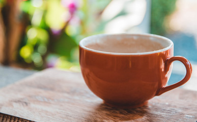 A cup of hot coffee that has been exhausted and a little bit of bubble milk left over in a cup placed on a wooden table.