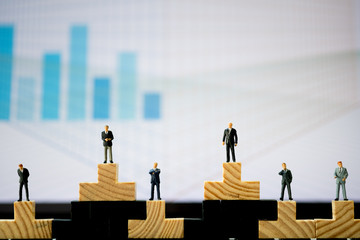 Miniature people: Each businessmen are standing on wood block in different position