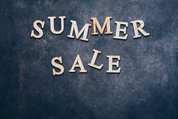 Summer sale-text in wooden letters on a dark rustic background, flat lay, copy space.