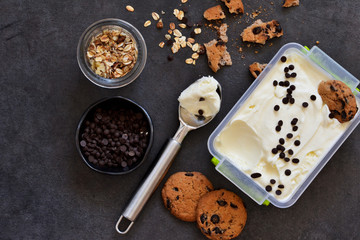 Vanilla ice cream with cookies, oatmeal and chocolate drops on a black background. Summer cold dessert.