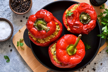 Red pepper stuffed with meat, bulgur and vegetables in a cast-iron pan. Baked stuffed peppers.